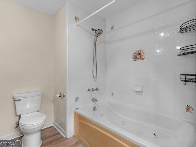 bathroom with tiled shower / bath combo, hardwood / wood-style flooring, and toilet