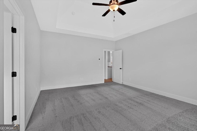 unfurnished room with ceiling fan, a tray ceiling, and carpet floors