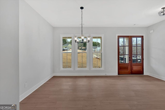 unfurnished dining area with hardwood / wood-style flooring, a healthy amount of sunlight, and an inviting chandelier