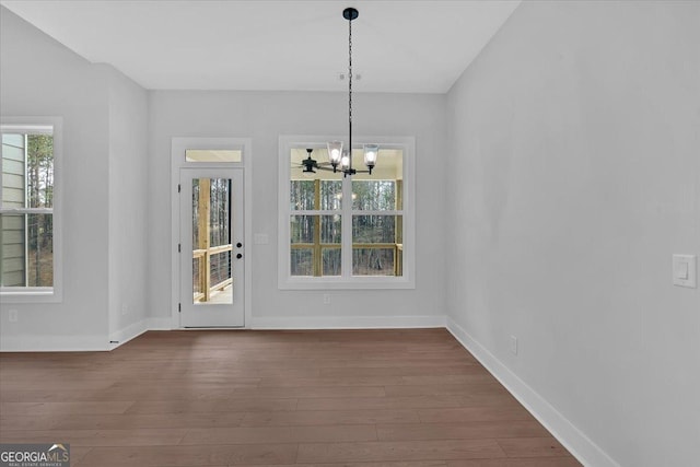 unfurnished dining area with dark hardwood / wood-style floors and a notable chandelier