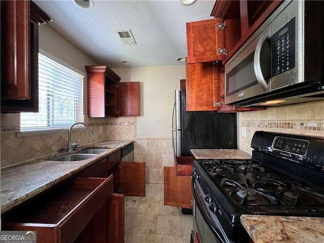 kitchen featuring light stone counters, sink, decorative backsplash, and stainless steel appliances