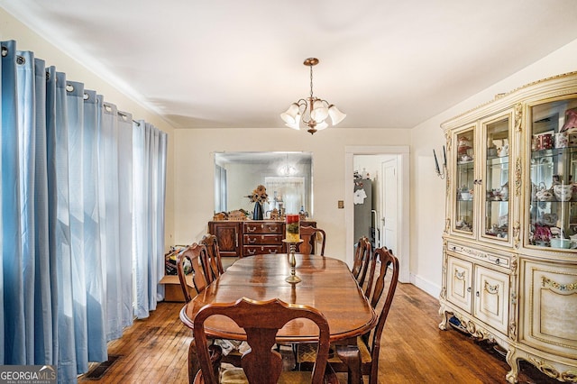 dining space with dark wood-type flooring and a notable chandelier