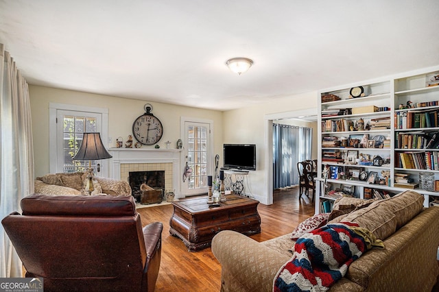 living room featuring wood-type flooring and a tiled fireplace