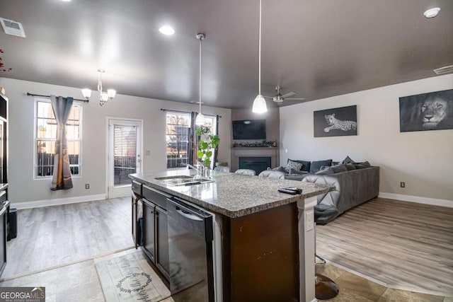 kitchen with dishwasher, sink, pendant lighting, a kitchen island with sink, and ceiling fan with notable chandelier