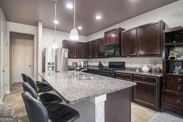 kitchen featuring sink, a center island with sink, a breakfast bar area, and black appliances