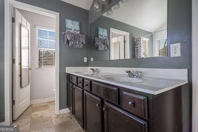 bathroom with toilet, vanity, and vaulted ceiling