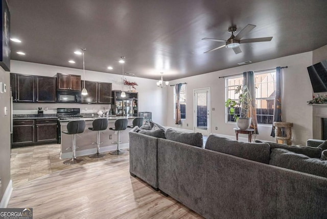 living room with light hardwood / wood-style flooring and ceiling fan with notable chandelier