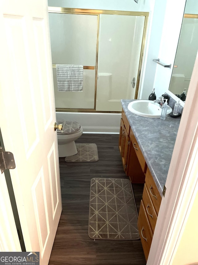 full bathroom featuring shower / bath combination with glass door, wood-type flooring, vanity, and toilet