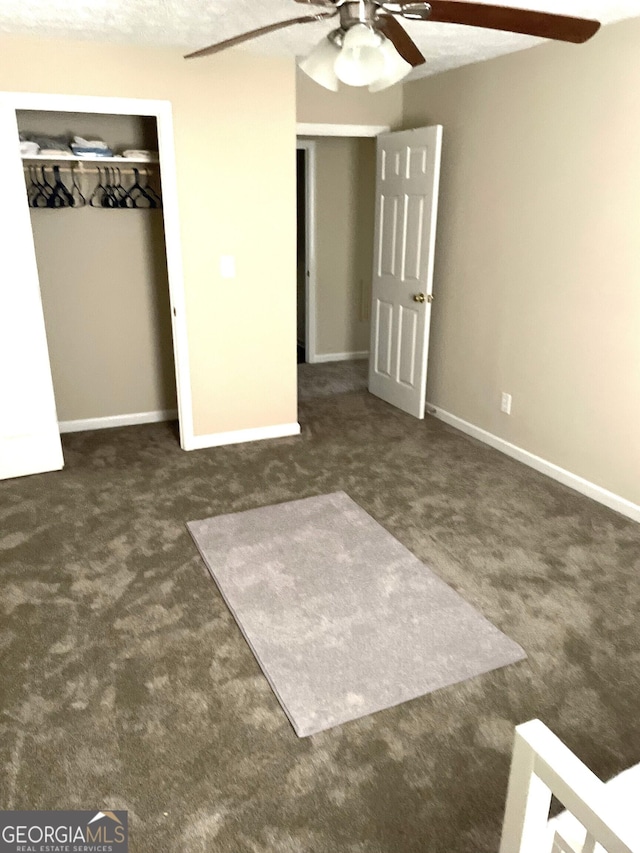 unfurnished bedroom with ceiling fan, a closet, a textured ceiling, and dark colored carpet