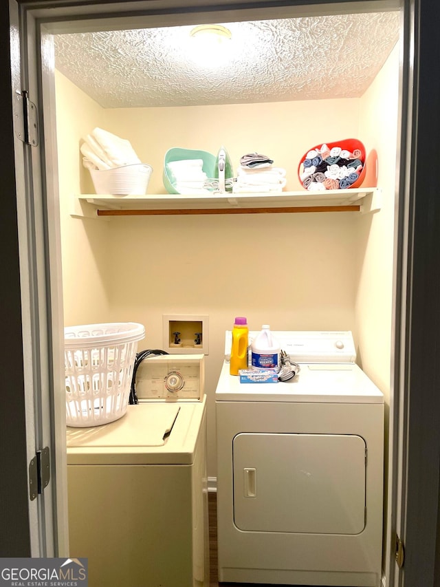 laundry area with separate washer and dryer and a textured ceiling