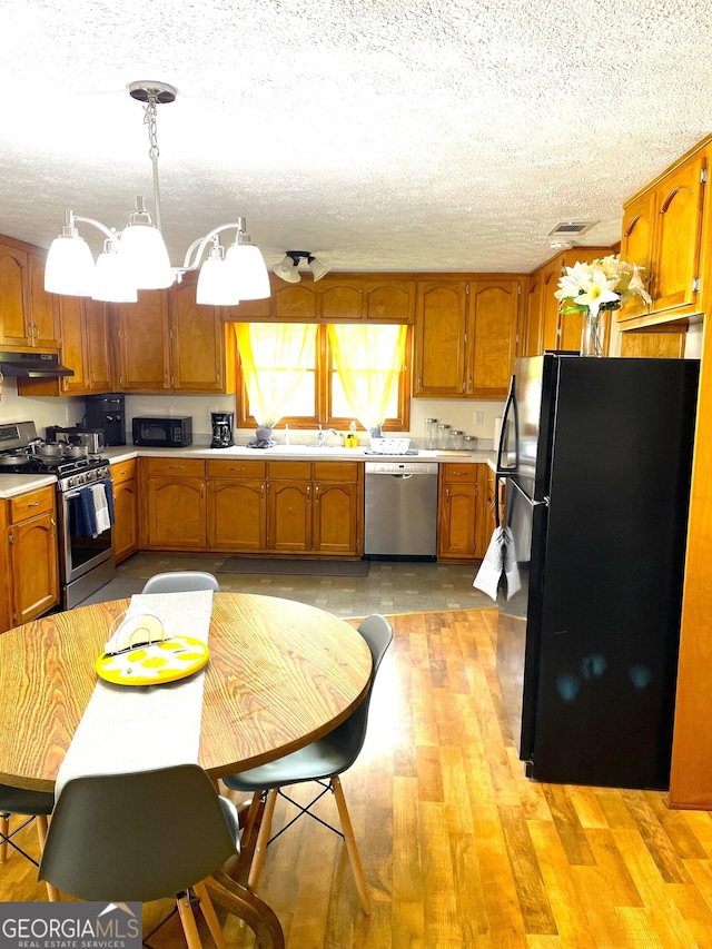 kitchen featuring a notable chandelier, pendant lighting, a textured ceiling, black appliances, and light wood-type flooring