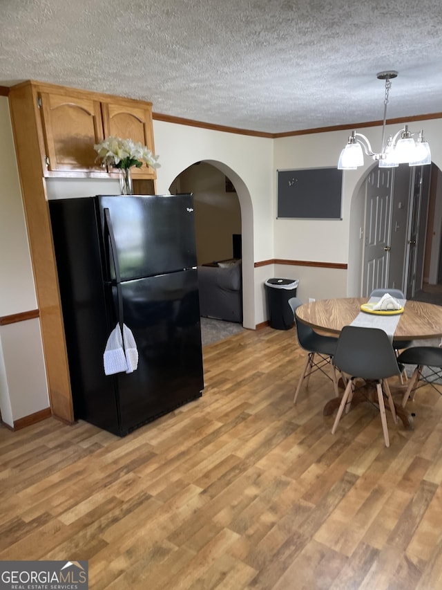 dining space featuring a textured ceiling, ornamental molding, light hardwood / wood-style flooring, and an inviting chandelier