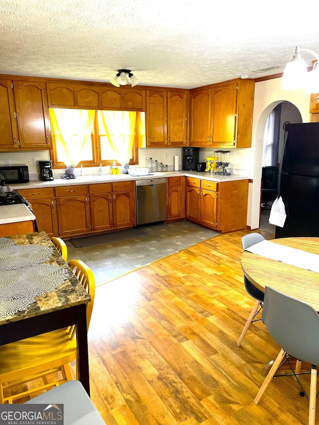 kitchen with light wood-type flooring, a textured ceiling, and black appliances