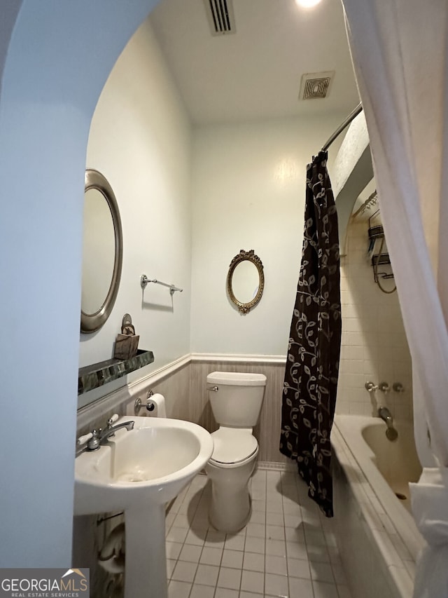 bathroom featuring toilet, wood walls, shower / bath combo with shower curtain, and tile patterned flooring