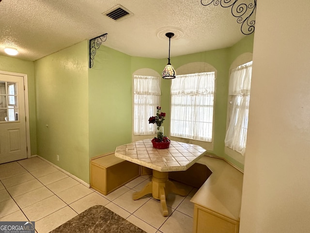 dining space featuring light tile patterned floors, a textured ceiling, and breakfast area