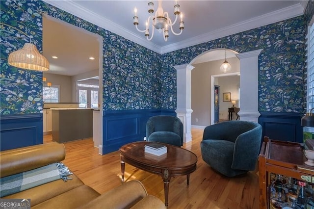 sitting room featuring wood-type flooring, ornamental molding, and an inviting chandelier