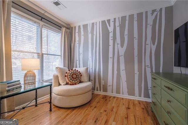 living area with light hardwood / wood-style floors and ornamental molding