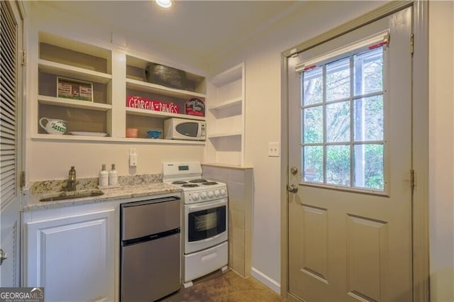 kitchen with white appliances, white cabinets, sink, built in shelves, and light stone counters