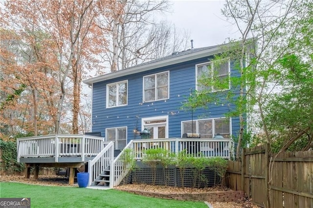 rear view of property with a deck and a lawn