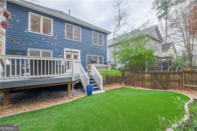 back of property with a yard and a wooden deck