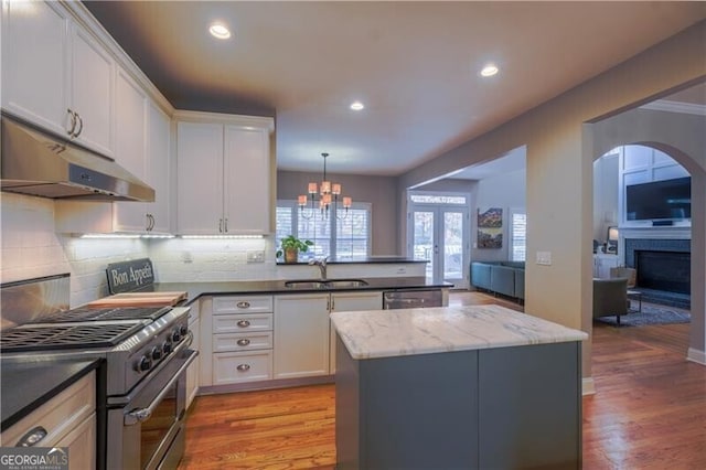 kitchen with stainless steel appliances, sink, pendant lighting, light hardwood / wood-style floors, and white cabinetry