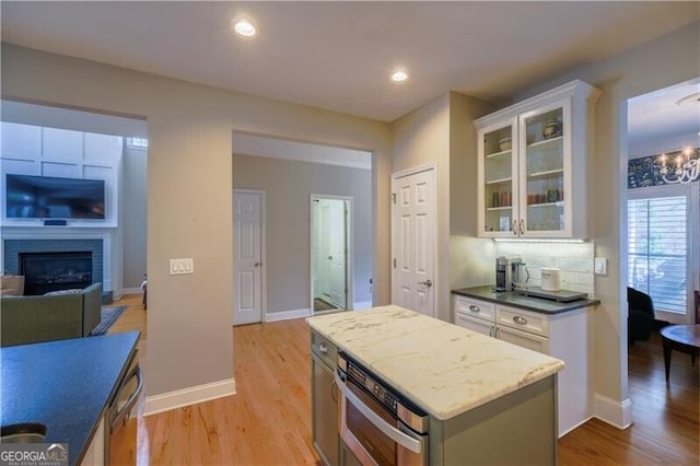 kitchen featuring a center island, light wood-type flooring, white cabinetry, and a fireplace