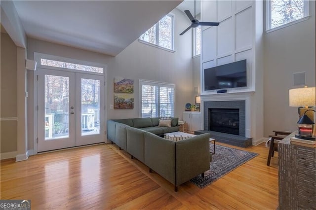 living room with a wealth of natural light, french doors, ceiling fan, and light wood-type flooring