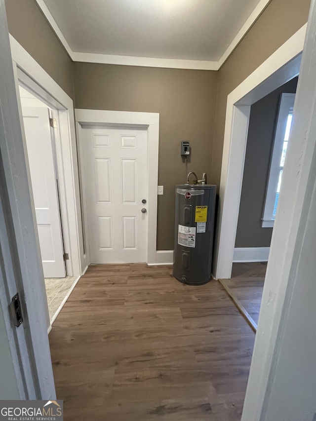 interior space with electric water heater, dark hardwood / wood-style flooring, and ornamental molding