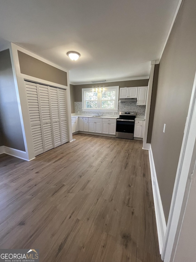 kitchen with stainless steel range with electric cooktop, tasteful backsplash, light hardwood / wood-style floors, white cabinetry, and a chandelier