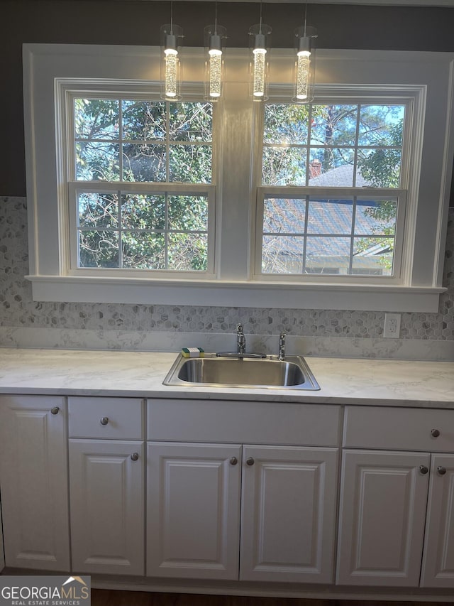 kitchen featuring decorative light fixtures, white cabinetry, plenty of natural light, and sink