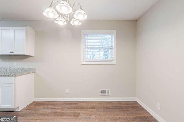 unfurnished dining area with light hardwood / wood-style flooring and an inviting chandelier