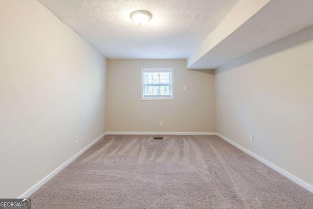 spare room featuring carpet flooring and a textured ceiling