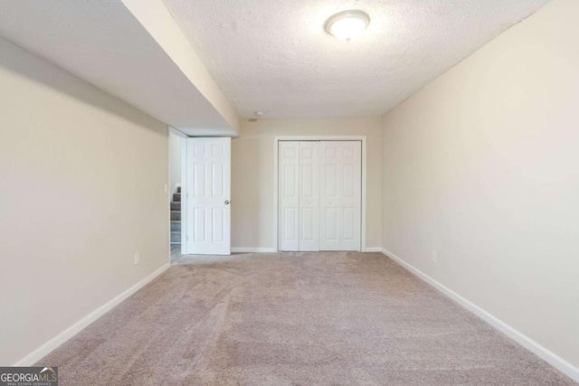 unfurnished bedroom with light colored carpet, a textured ceiling, and a closet