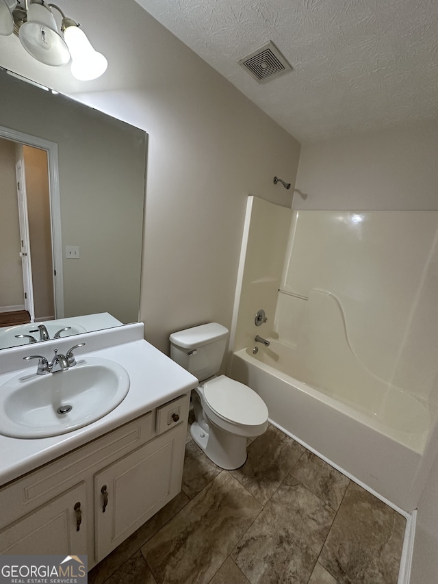 full bathroom with toilet, vanity, a textured ceiling, and washtub / shower combination