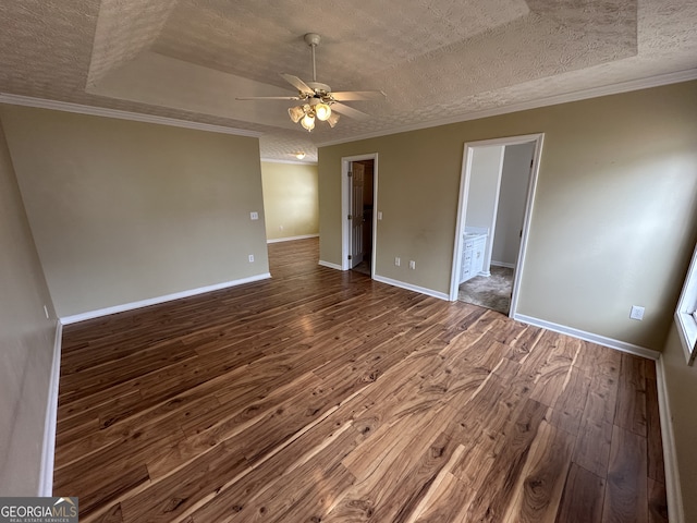 unfurnished room featuring hardwood / wood-style floors, ceiling fan, ornamental molding, a textured ceiling, and a tray ceiling