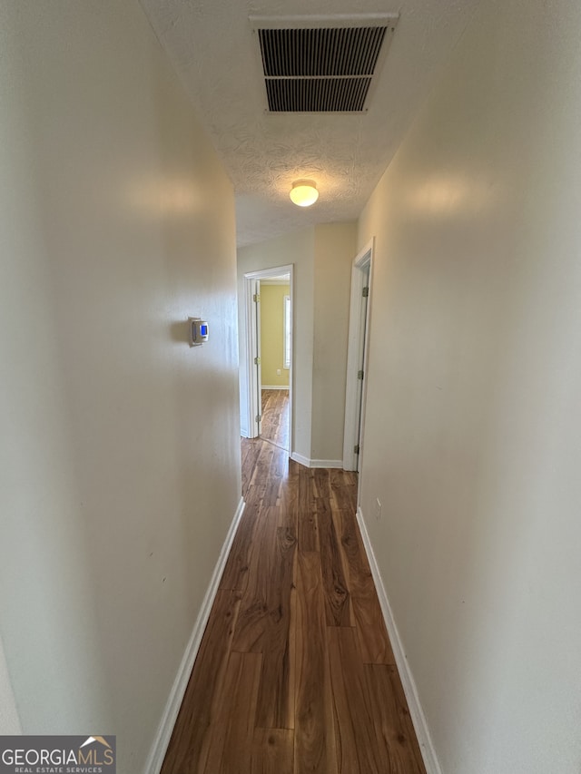 corridor with dark hardwood / wood-style floors and a textured ceiling