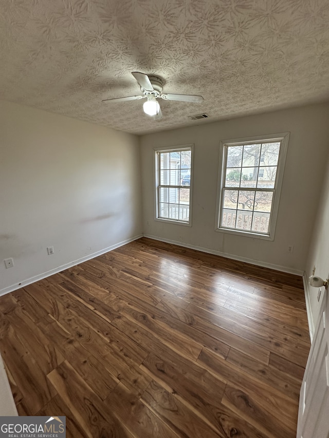 unfurnished room featuring a textured ceiling, ceiling fan, and dark wood-type flooring