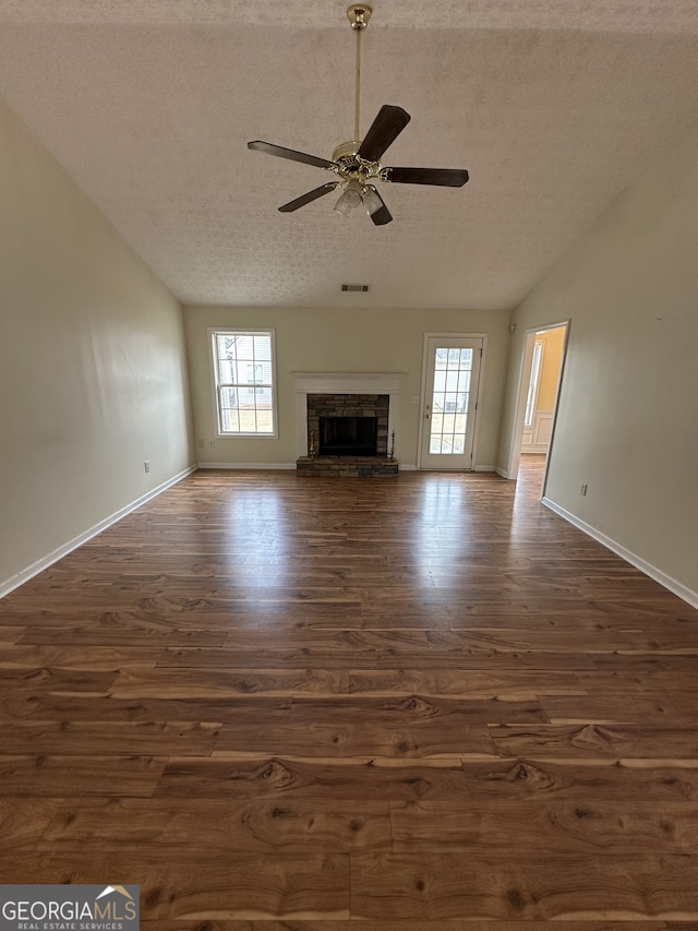 unfurnished living room featuring a textured ceiling, ceiling fan, dark hardwood / wood-style flooring, and a fireplace