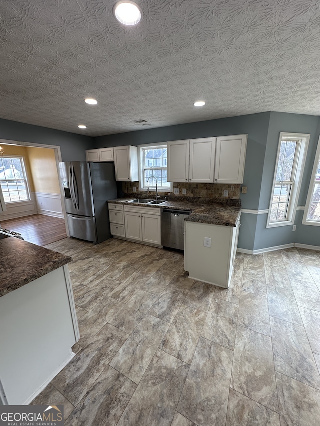 kitchen with decorative backsplash, appliances with stainless steel finishes, a textured ceiling, sink, and white cabinets