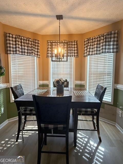 dining space with a textured ceiling, dark hardwood / wood-style floors, plenty of natural light, and a notable chandelier