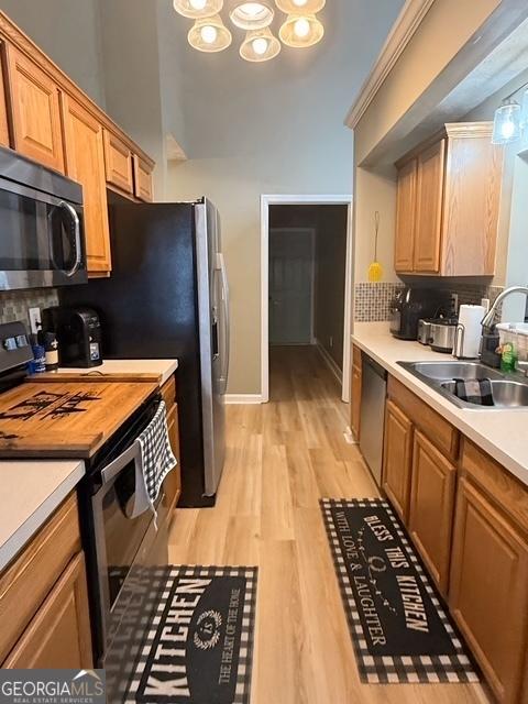 kitchen with tasteful backsplash, sink, stainless steel appliances, and light wood-type flooring