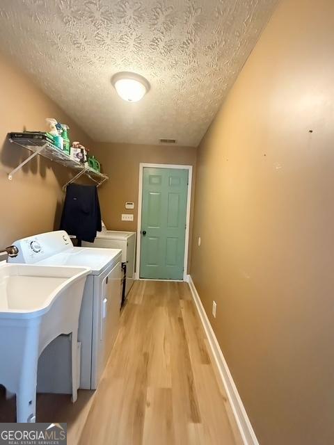 washroom with hardwood / wood-style floors, sink, washing machine and dryer, and a textured ceiling