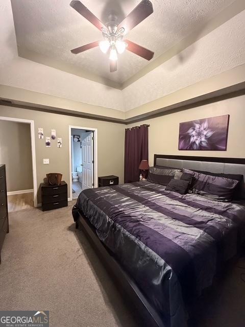 carpeted bedroom with a textured ceiling, a raised ceiling, and ceiling fan