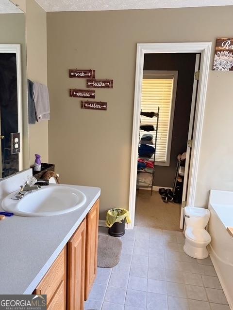 bathroom featuring a bathing tub, vanity, a textured ceiling, and tile patterned floors