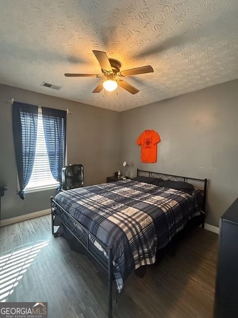 bedroom with hardwood / wood-style floors, a textured ceiling, and ceiling fan