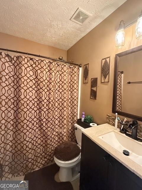 bathroom with vanity, toilet, and a textured ceiling