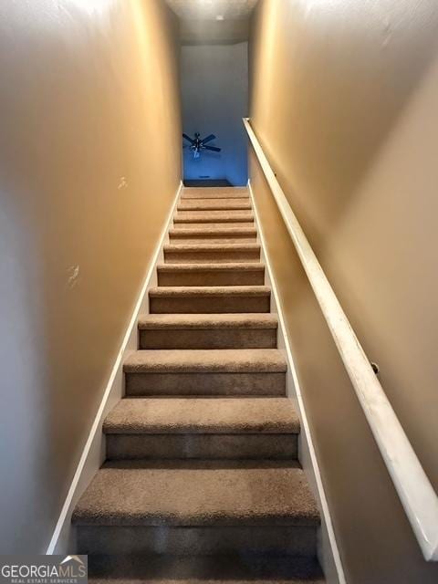 staircase featuring ceiling fan