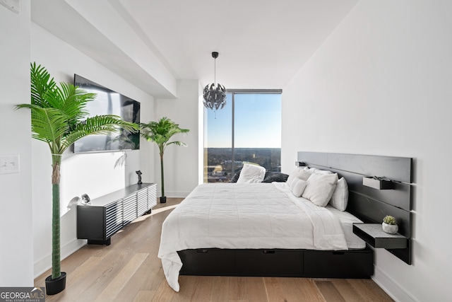 bedroom with expansive windows, a chandelier, wood finished floors, and baseboards