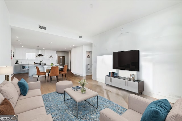 living area with light wood finished floors, visible vents, and recessed lighting