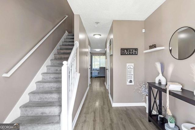 stairway with a textured ceiling and hardwood / wood-style flooring